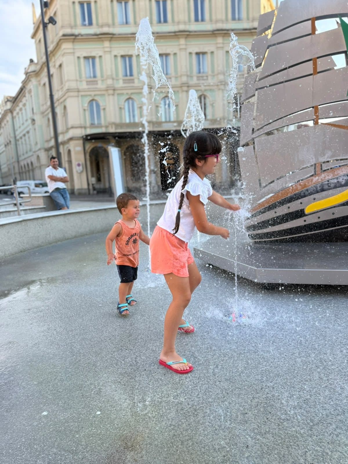 Two children playing in a fountain on a summer day