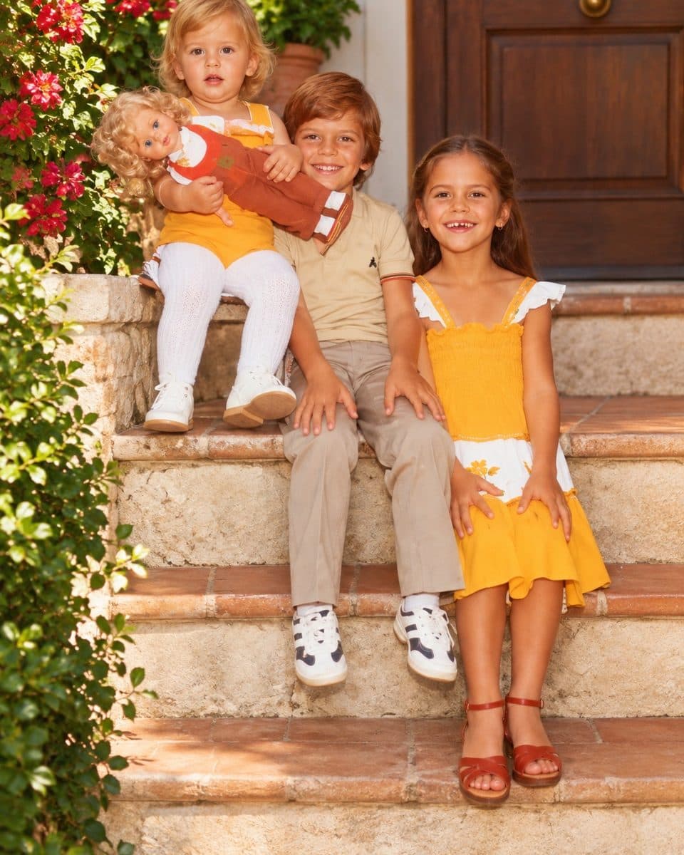 Three children smiling on the garden steps