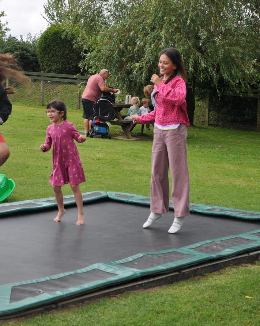 Vanessa bouncing with children on a garden trampoline