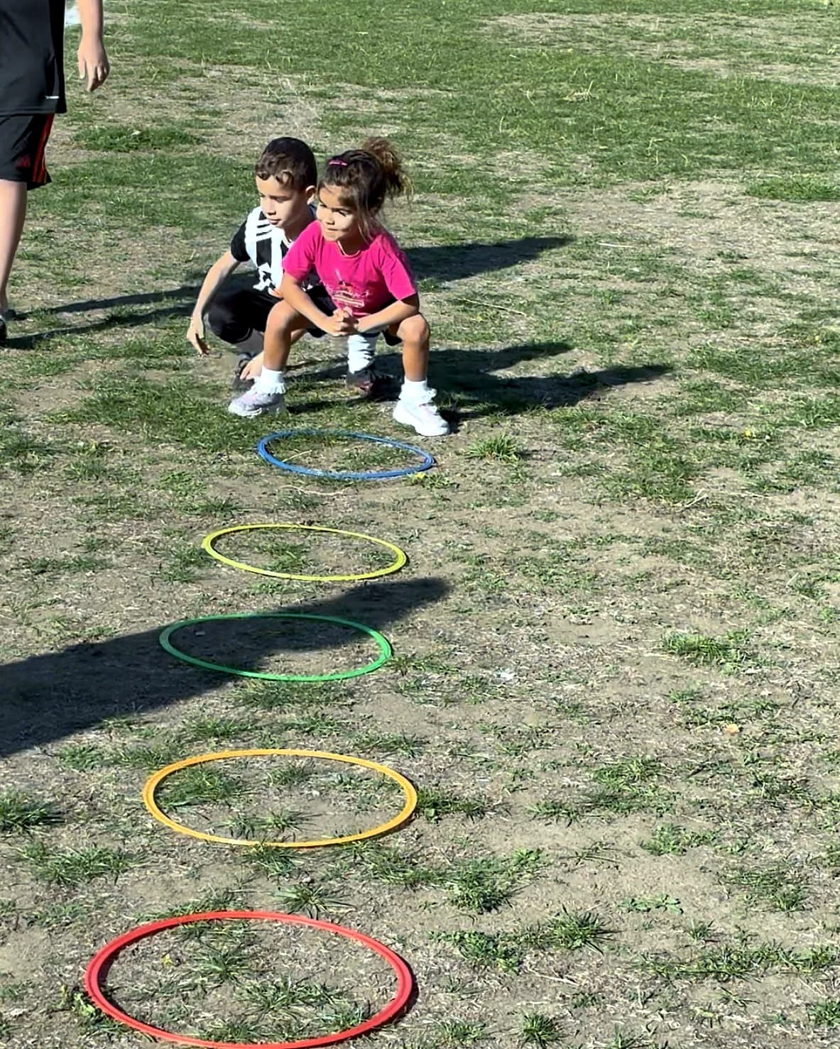 Two children crouching at the start of a hoop course