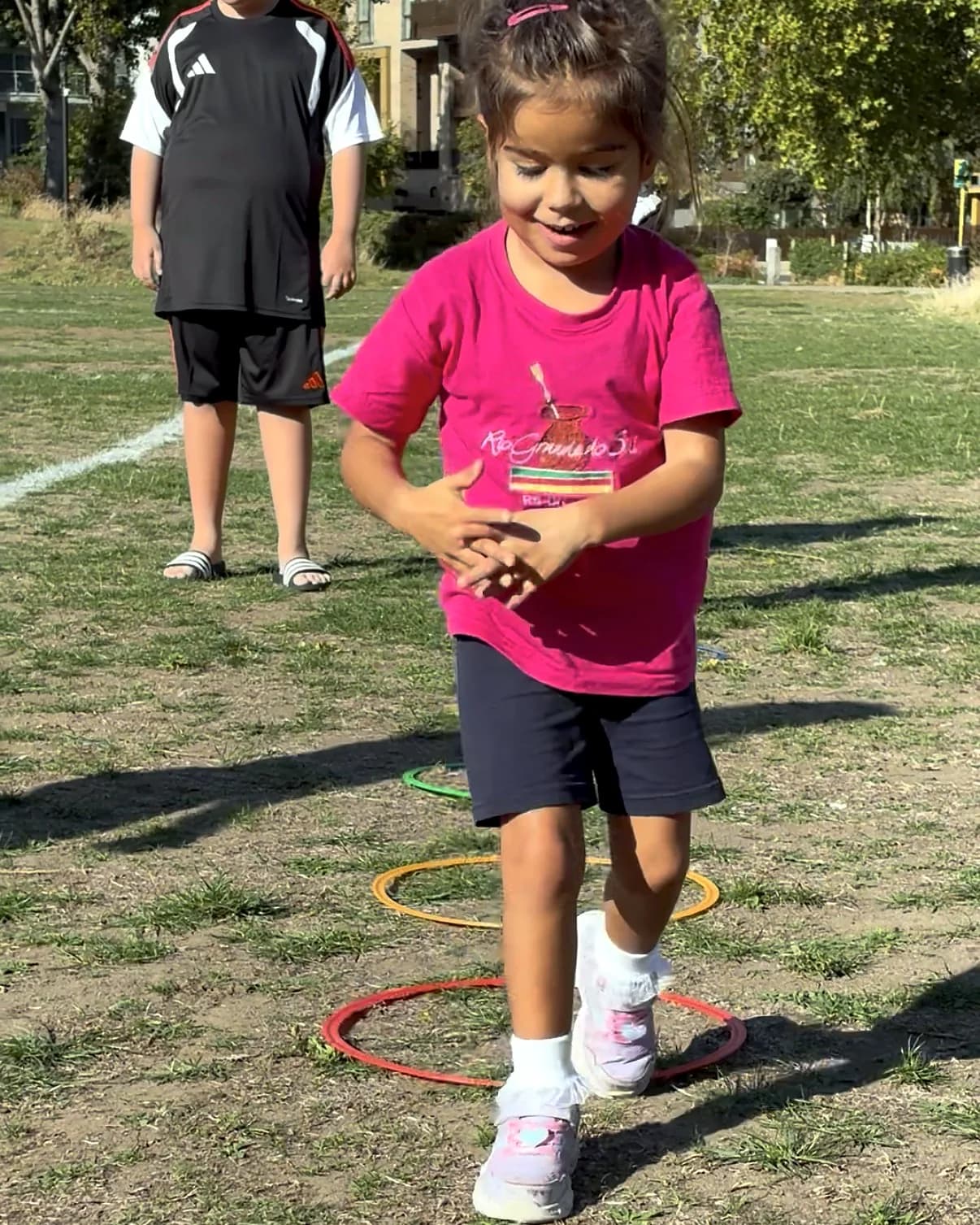 A child smiling as she steps through the hoops