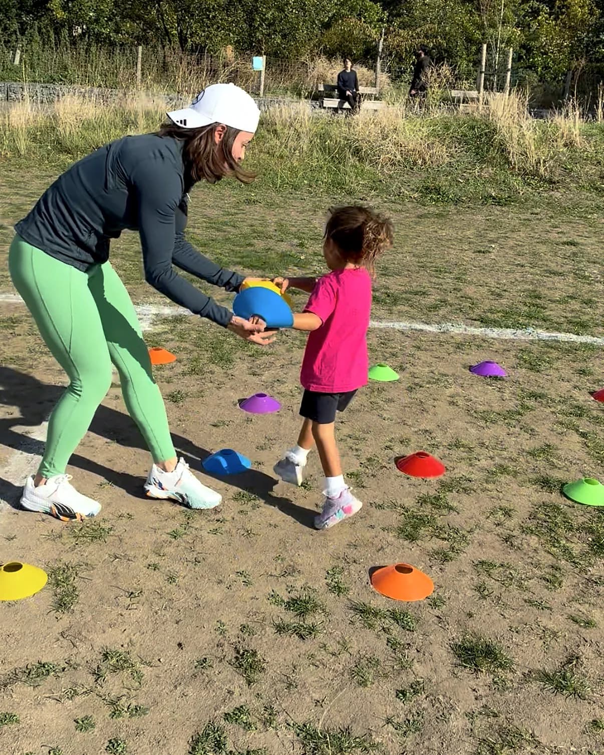 Vanessa passing a disc cone to a child among coloured markers
