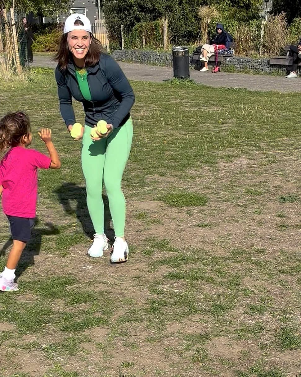 Vanessa smiling with tennis balls in hand at a park session