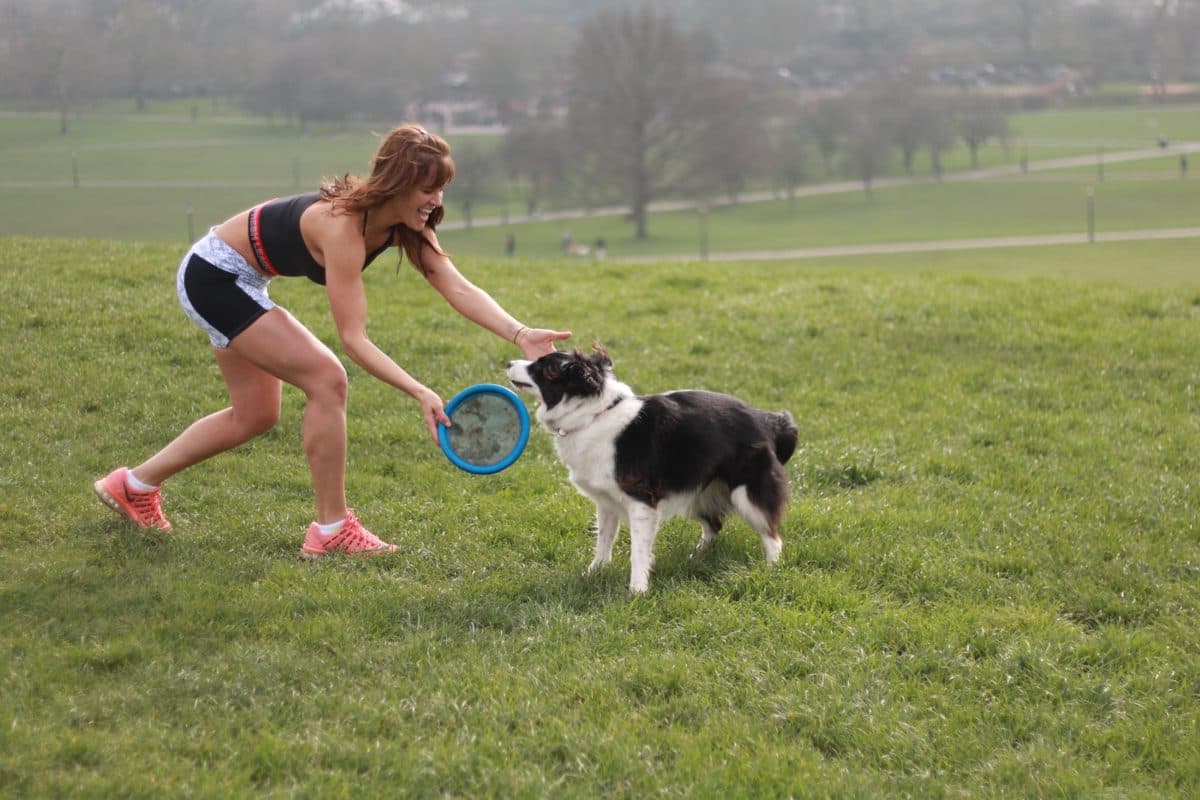 Vanessa playing frisbee with her dog on the grass